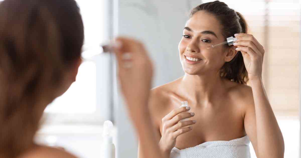 a beautiful woman putting some skin secrets drops on her face